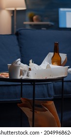 Close Up Of Table With Food And Booze Leftover On Misery Table In Empty Unorganized Messy Living Room Of Depresive Person. House Apartment Of Alone Woman With Sever Depresion