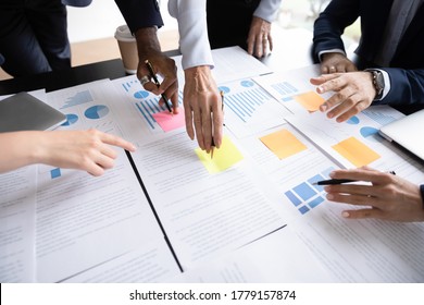 Close up table full of papers, diverse businesspeople analyzing report in charts and graphs discuss paperwork data statistics at group meeting. Research overview activity, brainstorm teamwork concept