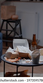 Close Up Of Table With Leftover On It In Empty Unorganized Messy Living Room Of Depresive Person. House Apartment Of Alone Woman With Sever Depresion Having Trash, Rubbish, Napkins On Blue Sofa