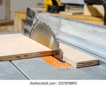 Close up of table saw circular blade cutting through a birch plywood sheet  selective focus on saw blade