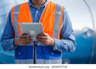 close up tablet with man engineer working at rooftop building. Engineering installing large air conditioning system. - Powered by Shutterstock