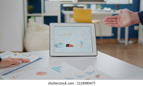 Close up of tablet and papers with data charts on desk used by workmates for business development. Corporate colleagues working on project presentation for management and marketing strategy