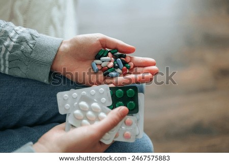 Close up tablets of different colors in hands of unrecognizable, many pills and medications. Health concept. Medicine. Serious illness. Long term treatment. Indoor, at home.