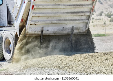 Close Up Of The Tailgate On A  Dump Truck Spreading Gravel On A Dirt Driveway