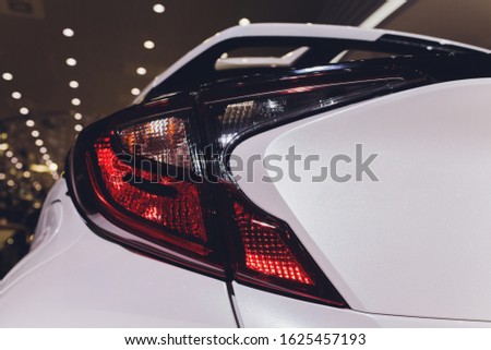 Close up of taillight detail of modern luxury sportscar with reflection on white paint after wash wax. Rear view of supercar break lights. Concept of car detailing and paint protection background.