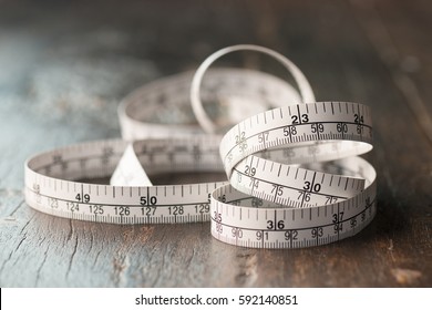 Close up tailor measuring tape on wooden table background. White measuring tape shallow depth of field.