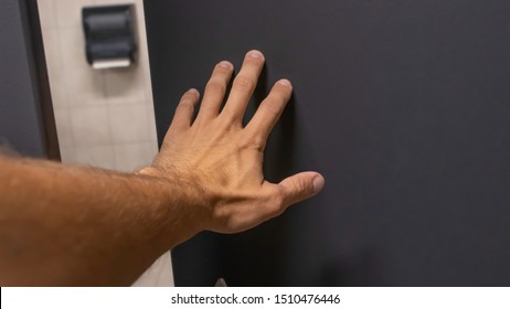 Close Up Of Tan Hairy Man Hand Pushing Open A Grey Blue Bathroom Stall Door From Inside Under A Warm Light Front Point Of View Perspective Angle.