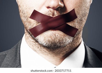 Close up of taped caucasian businessman mouth. Silence and speech censorship concept