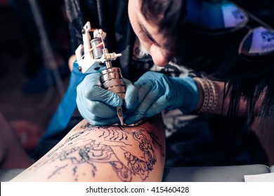 Close up tattoo artist demonstrates the process of getting black tattoo with paint. Master works in black sterile gloves. Master of tattoo fill circuit tattoo. - Shutterstock ID 415460428