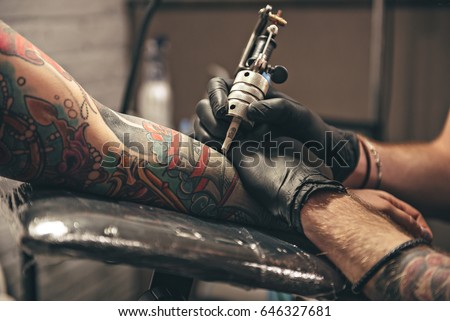 close up tattoo machine. Man creating picture on hand with it in salon