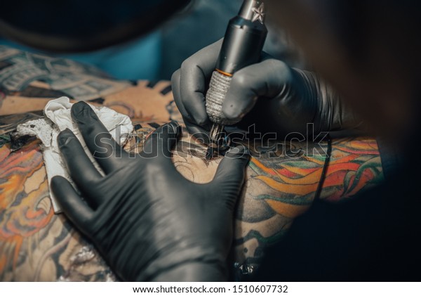 Close up of the\
tattoo machine. Tattooing. Man creating a picture on his back by a\
professional tattoo\
artist.