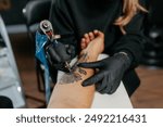 Close up tattoo master  professional tattoo artist in black gloves making a  rose tattoo on a man