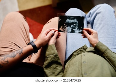 Close Up Of Tattooed Gay Couple With Pregnant Young Woman Looking At Ultrasound Image Of Baby, Same Sex Family