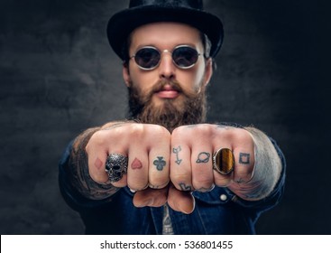 Close up tattooed hipster's fingers with rings.