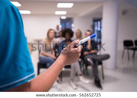 close up of teacher hand with marker while teaching lessons in school classroom to multiethnic students