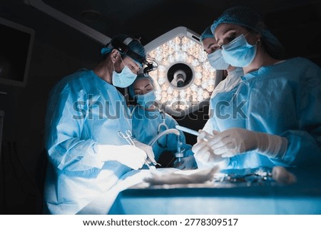 Close teamwork of surgeons performing operation in operating theater, medical staff in sterile uniforms, advanced surgery and healthcare concept