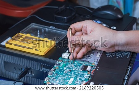 Close up of Technician Hand using Screwdriver to Assembling Maintenance the motherboard Hardware of Laptop computer