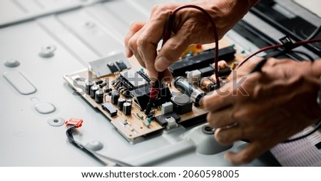 Close up of Technician measuring voltage electronic circuit board television, Service after sale fix electric equipment within insurance.