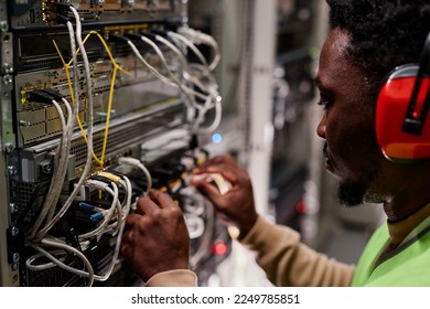 Close up of technician setting up network in server room and wearing ear protection