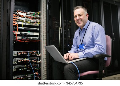 Close Up Of Technician Using Laptop In Server Room At The Data Centre