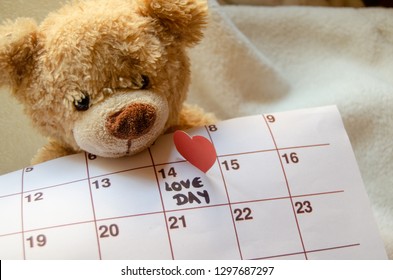 Close up of teddy bear holding callendar and paper red heart marking love day 14 february - Valentine's day concept