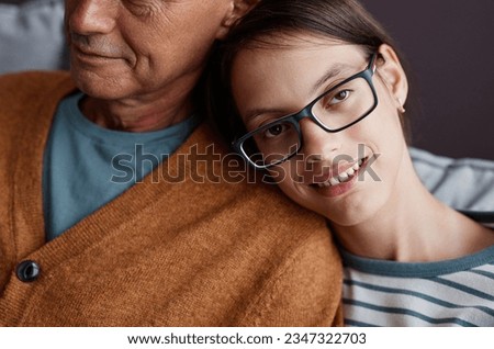 Close up of teen girl with cerebral palsy leaning head on fathers shoulder and smiling at camera