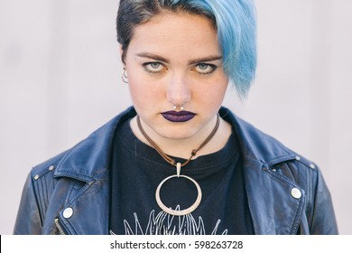 Close Up Of A Teen Punk Woman With A Nose Piercing, Dyed Blue Hair And Dark Lips Isolated On The Street