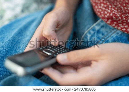 Close Up Of Teenage Girl Using Basic Dumb Push Button Mobile Phone For Messaging With No Online Connection