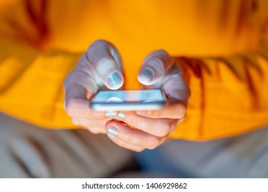 Close up of teenager or adult woman playing online and sending text on smart phone with a colorful background light from the screen in Mobile addiction Internet gaming Connections and New technology.