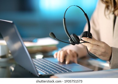 Close up of a tele marketer holding headset using laptop at homeoffice