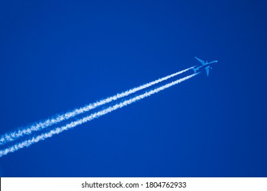 Close up telephoto image of jet airplane with contrails or vapor trails  flying from Tokyo to Detroit and cruising at 41,000 feet at a ground speed of 535 knots