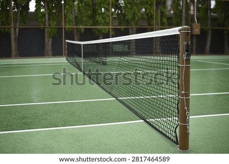 Close up of a tennis net on an empty green hard court outdoors, ideal for sports, recreation, and facility concepts.