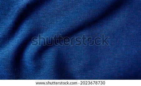 close up texture of creased fabric. blue woolen fabric. blue wavy cloth background showing fiber detail. blue fabric background with beautiful light and shadow.