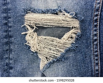 Close up texture of ripped destroyed torn jean or hole and threads
