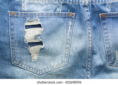close up of textures ripped blue jeans back pocket