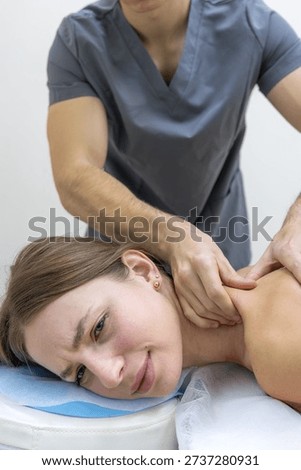 Close up of a therapist using deep thumb pressure on the patient neck and shoulder in a rehabilitation center. Soft daylight and minimal background emphasize focus, mobility and painrelief care.