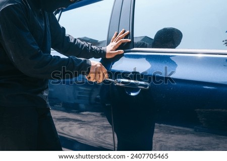 Close up of a thief trying to break into car with screwdriver. 