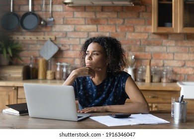Close up thoughtful African American woman touching chin, sitting at table with laptop and calculator, pondering strategy, businesswoman or student working on research project, planning budget