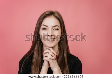 Close up of thoughtful blonde looks at camera, bites her lip, folded her hands, intertwined her fingers on a pink background. Dreaming girl  imagining her dreams come true. Positive people, mockup.