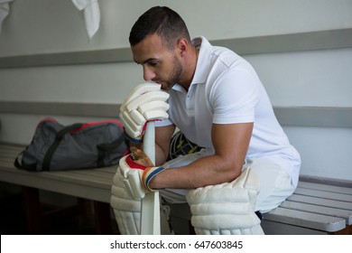 Close up of thoughtful cricket player sitting on bench at locker room - Powered by Shutterstock