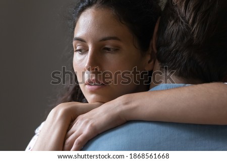 Close up thoughtful young woman hugging man, looking in distance, thinking about marriage problems, suspicious doubting wife embracing husband, pondering cheating in relationship, break up