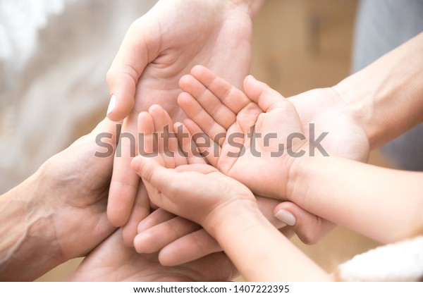 Close up of three caucasian person stack their\
palms. Grandmother mother and granddaughter holding their hands\
together. Gesture sign of support and love, unity togetherness\
relative people concept