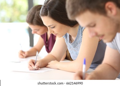 Close up of three concentrated students doing an exam in a classroom