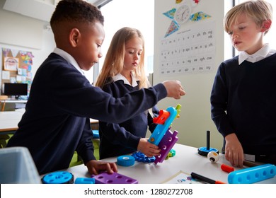 Close Up Of Three Primary School Children Working Together With Toy Construction Blocks In A Classroom, Side View