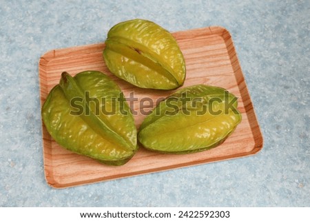 close up of three star fruits Carambola on a wooden tray on a blue pattern table