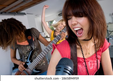 Close Up Of Three Teenage Girls In A Garage Band With One Teenage Girl Singing In The Foreground