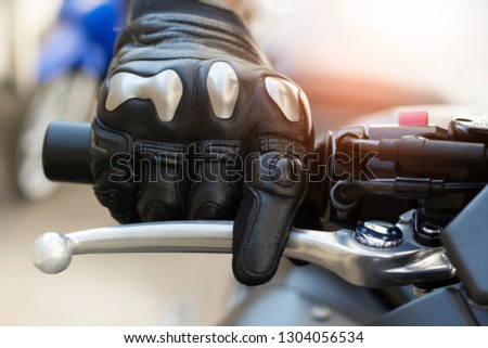 Close up of throttle control hand and brake lever motorcycle,Hands wearing black leather gloves with a protective card grip the brake lever.