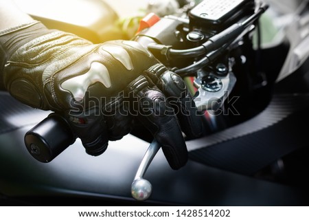 Close up of throttle control hand and brake lever motorcycle, Hands wearing black leather gloves with a protective card grip the brake lever