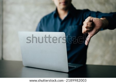 Close up of thumbs down and working on laptop.