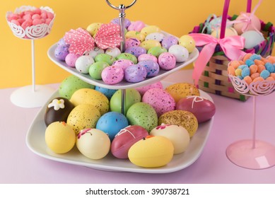 Close Up Of Tiered Server Tray With Assorted Chocolate Easter Eggs On Yellow Background.